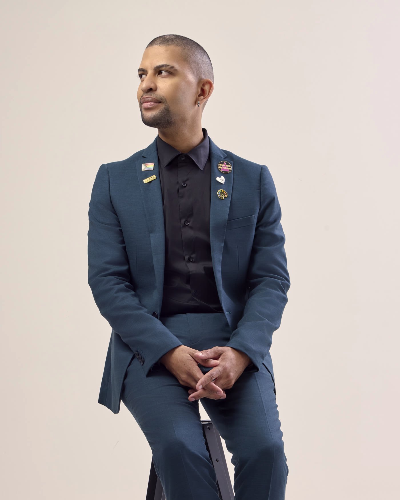 Traidy Bugeja-Naidoo seated, hands clasped, in a studio portrait.